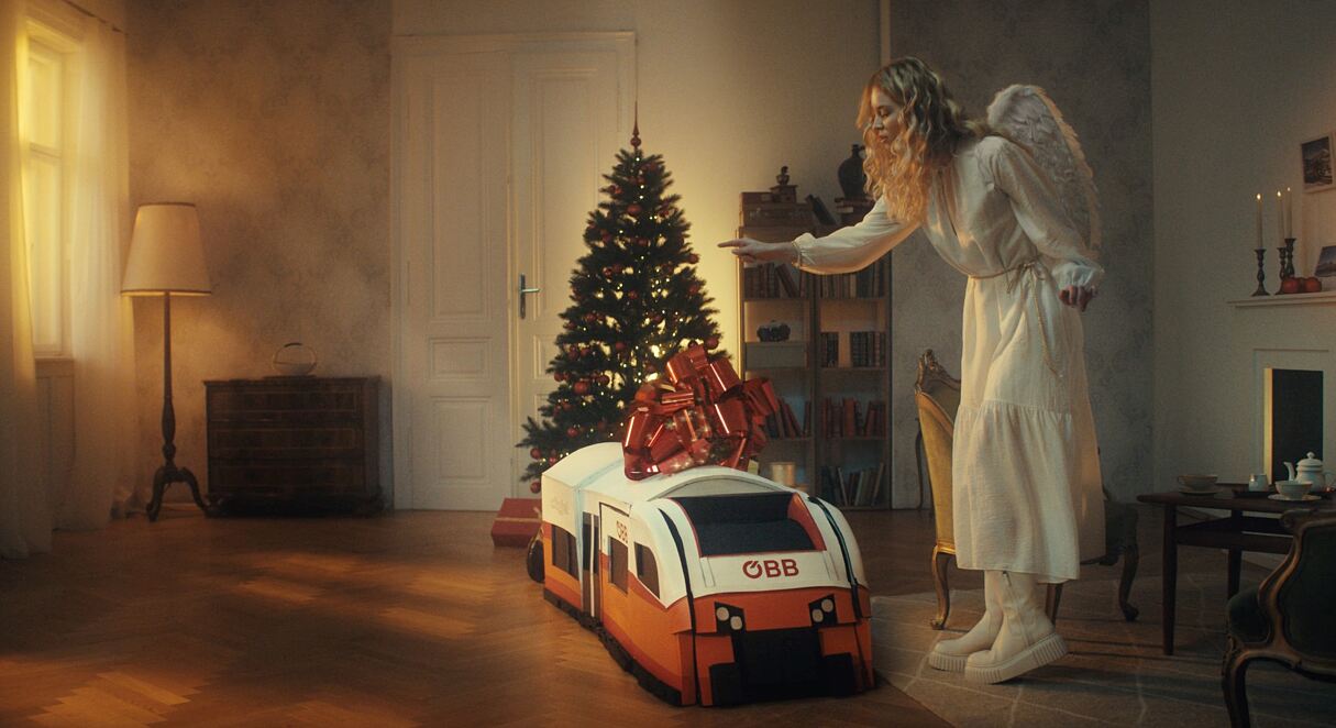 Das Christkind begutachtet stolz das Geschenk der ÖBB an ihre Kund:innen. 